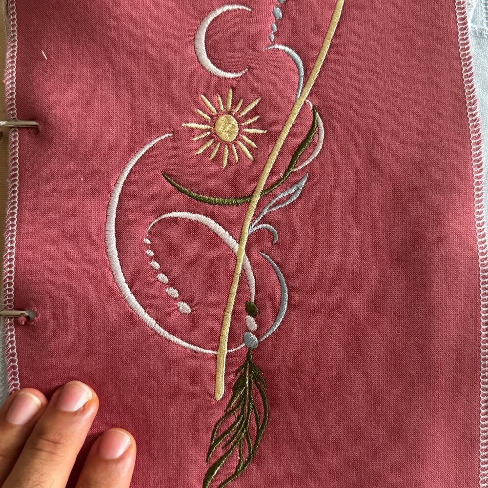 Besticktes Motiv mit Mond, Sonne und Federanhänger auf Textil